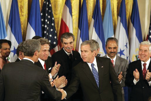 An image of George W. Bush shaking hands with legislators and administration officials.