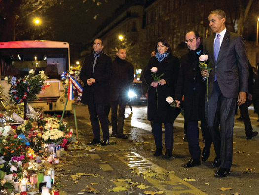 An image of Barack Obama, François Hollande, and Anne Hidalgo laying roses at a makeshift memorial.