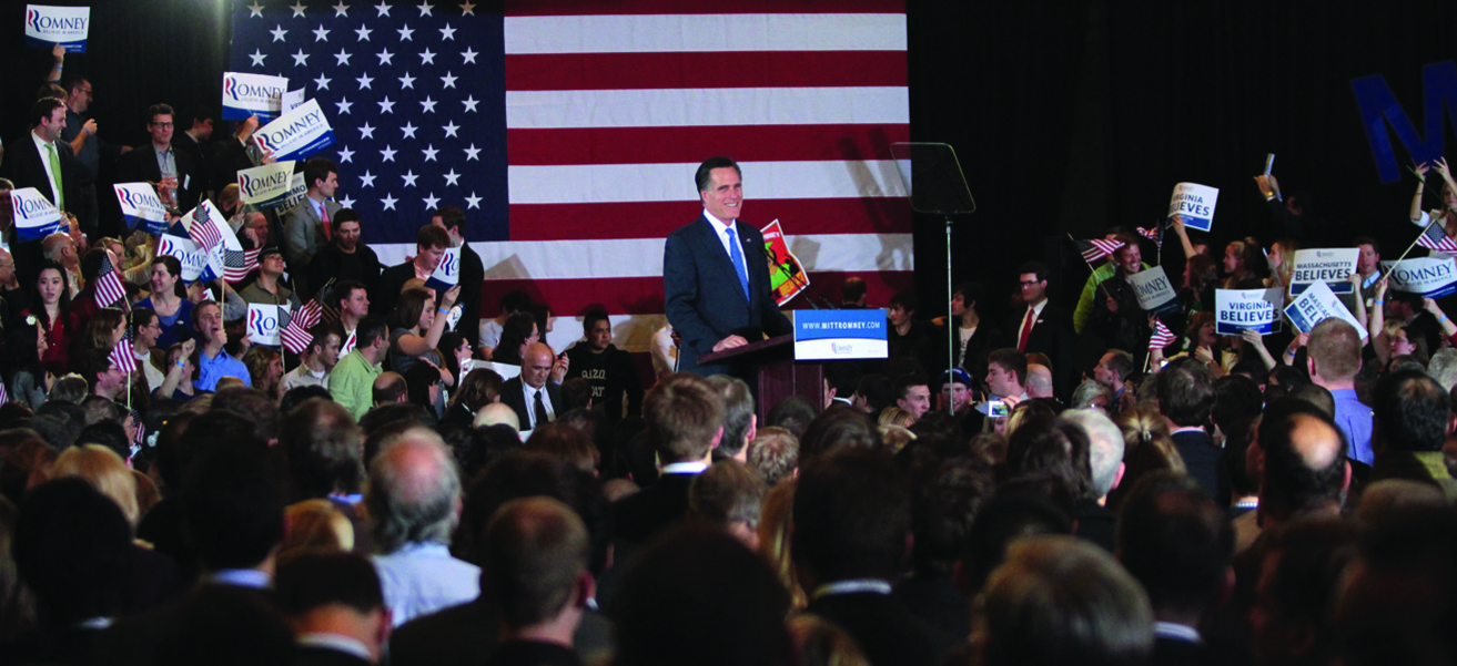 Photo of Mitt Romney in front of a crowd, smiling.