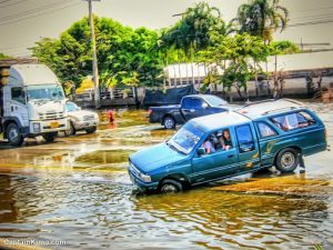 Blue car driving through a recently flooded area in Bangkok, Thailand.