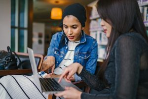 Two women interacting with information on a laptop computer