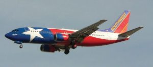 Airplane flying in the sky is painted red, white, and blue imitating the American flag.