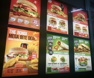 Oporto drive thru menu at night in Sydney, Australia. The screen reads "The Bondi Mega Bite Deal".