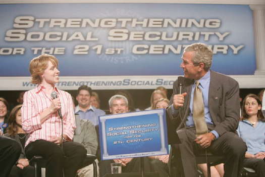 A photo of George W. Bush speaking at an event. The banner behind him says “Strengthening Social Security for the 21st Century.”