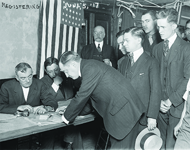 A photograph shows a group of young men registering for military conscription.