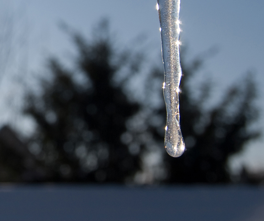 The given figure shows a vertically downward, knife-shaped ice piece, with water droplets sparkling on its surface.