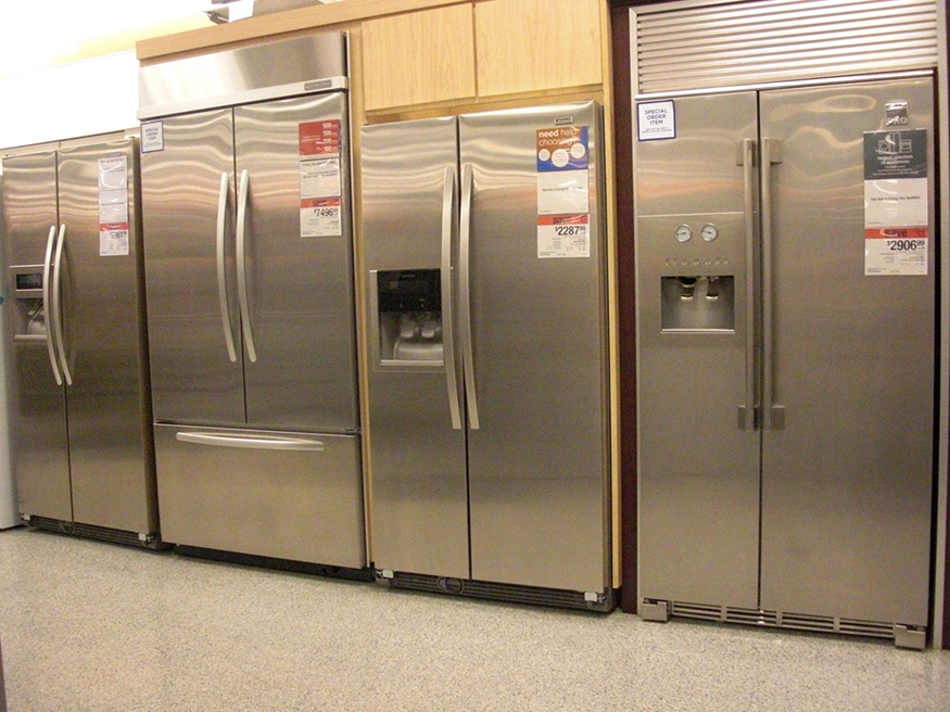 Photograph of various expensive refrigerators displayed in a home appliance store.