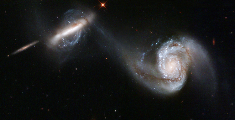 Two spiral galaxies show the strong gravitational attraction between them as their arms appear to reach out toward one another.